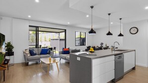 Eine moderne Küche mit Kochinsel, Essbereich mit Sofa und Couchtisch sowie ein großes Fenster für natürliches Licht.