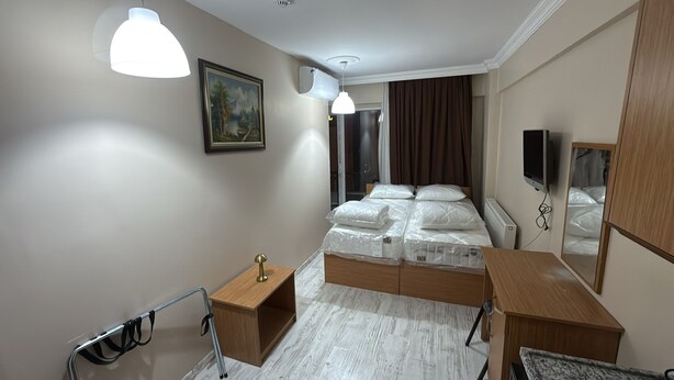 Un dormitorio moderno con cama de madera, una mesita de noche, un escritorio, una silla, una silla de ruedas y un espejo grande.