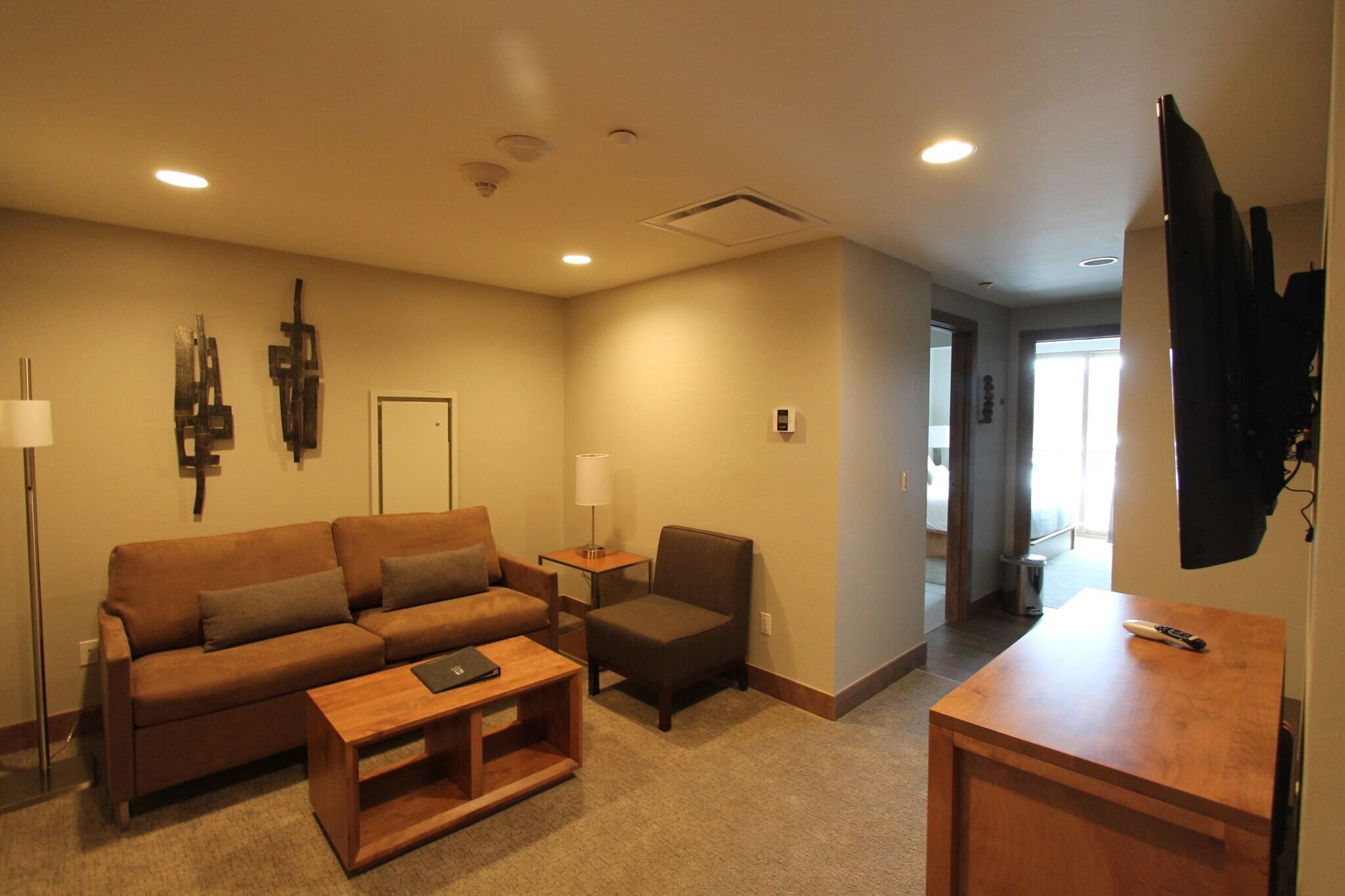 A living room with a sofa, armchair, coffee table, and a TV stand.