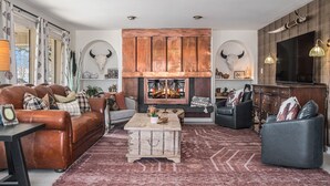 Una sala de estar con chimenea, sofás de cuero, una mesa de centro y un espejo grande.