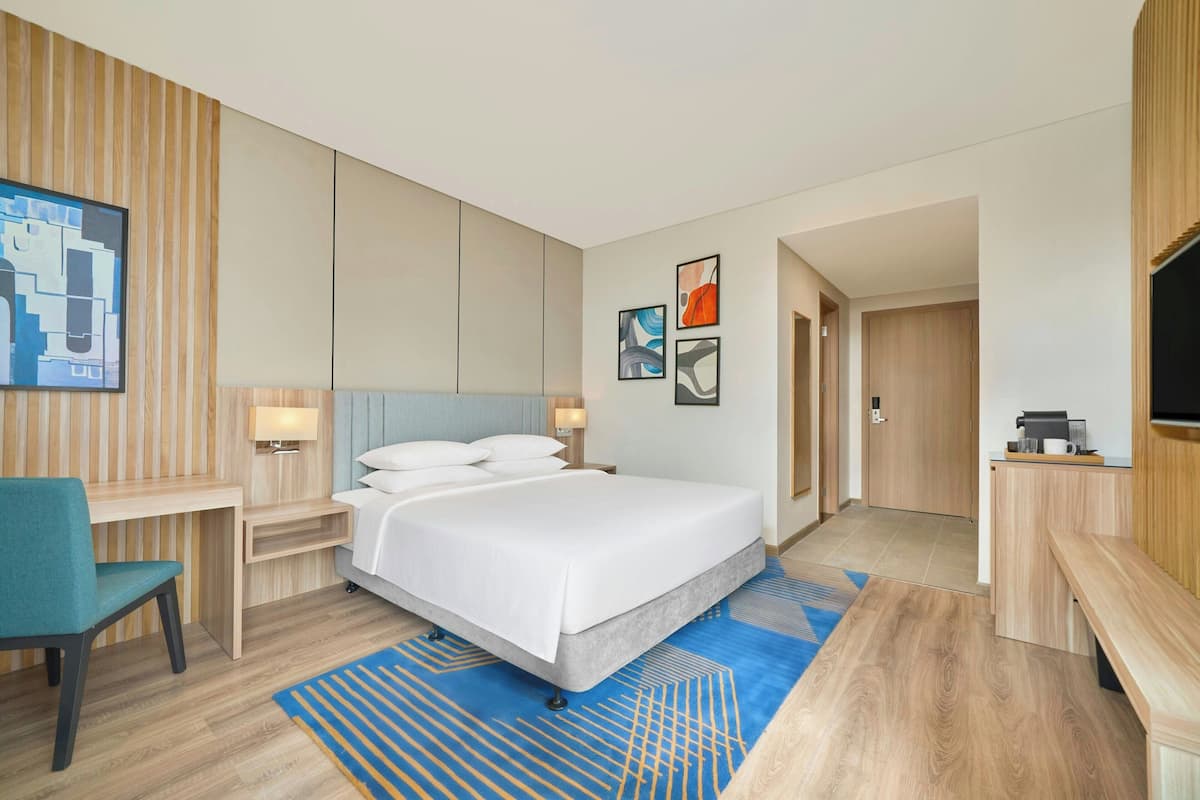 Une chambre d’hôtel moderne équipée d’un grand lit, d’un bureau, d’une chaise et d’une télévision.