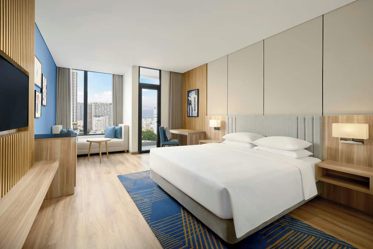 Une chambre d’hôtel moderne équipée d’un grand lit, d’un bureau, d’une chaise et d’un téléviseur.