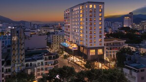Ein Hochhotel mit zahlreichen Etagen, einem Pool auf dem Dach und einer gut beleuchteten Fassade.