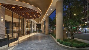 Ein moderner Hotelzugang mit gewölbter Decke, großen Fenstern und einem gut beleuchteten Weg.