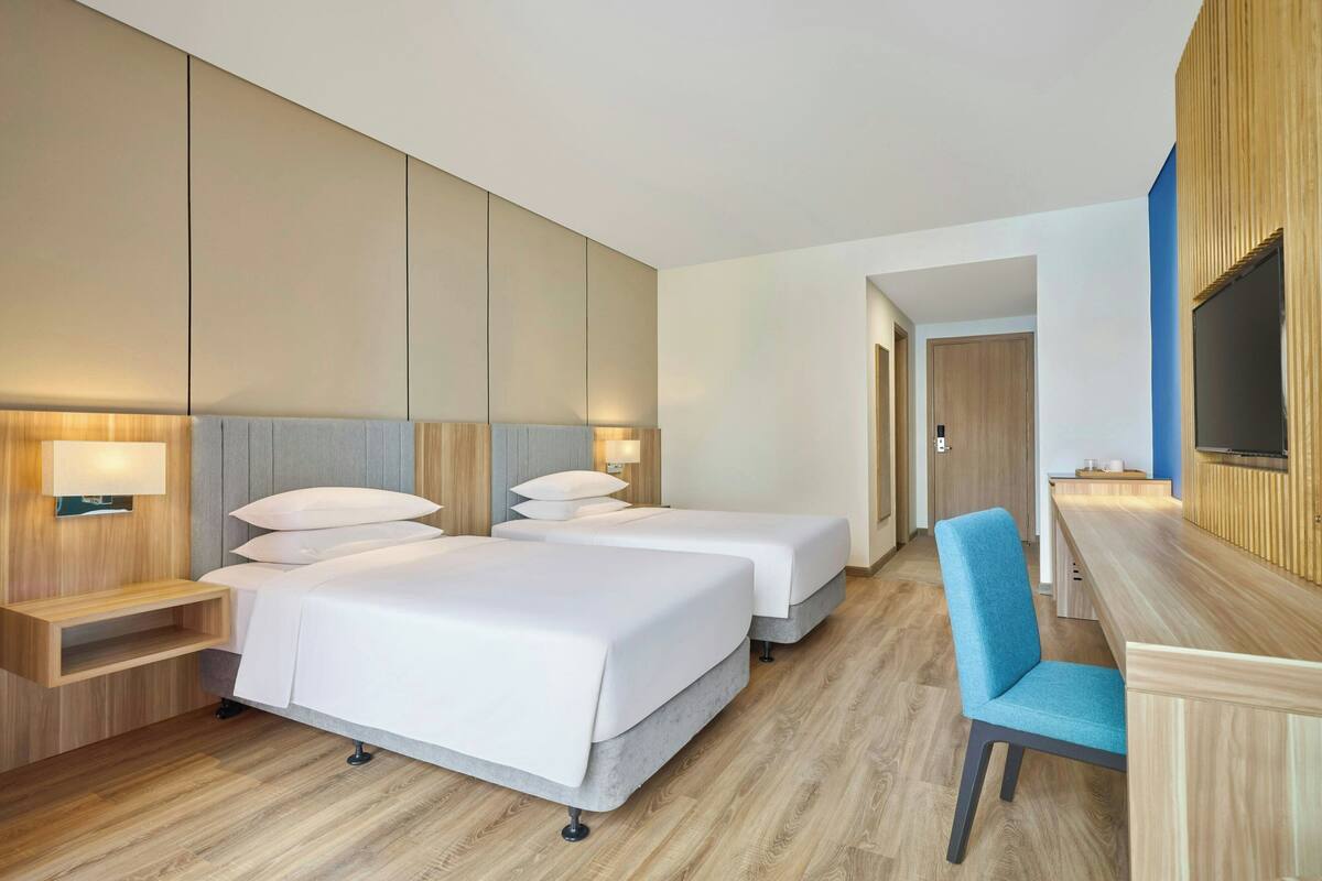 Une chambre d’hôtel avec deux lits, un bureau et une chaise.