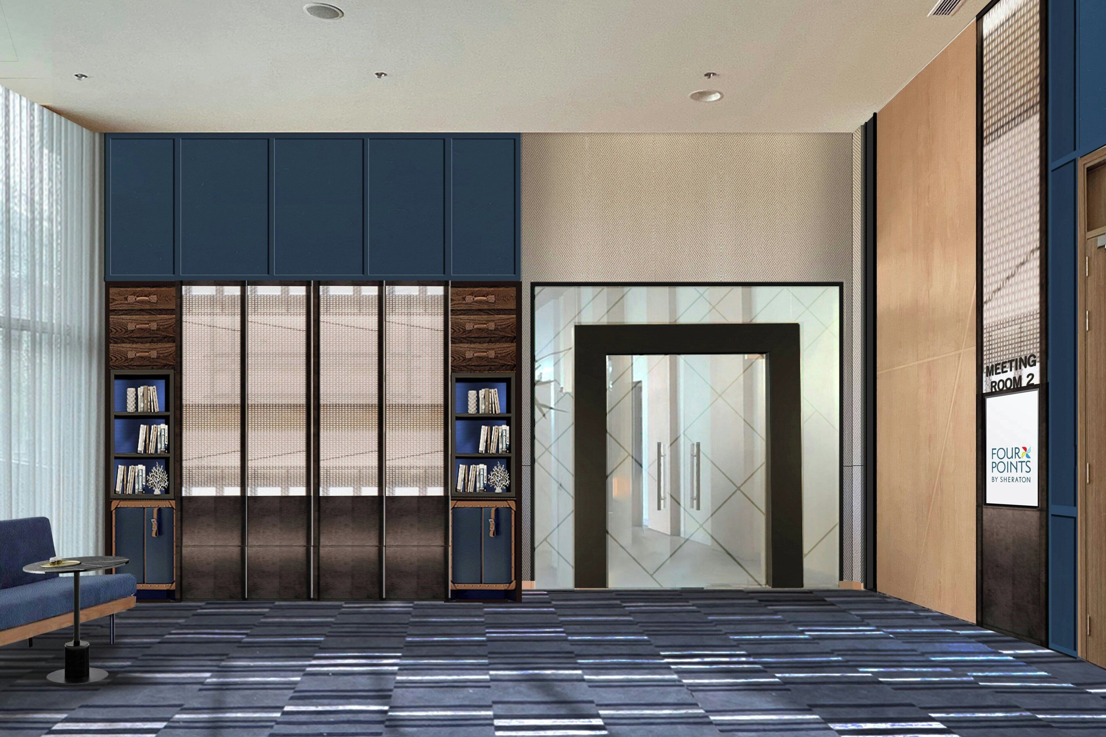 A modern lobby with a patterned floor, a seating area with a sofa and a small table, and a bookshelf.