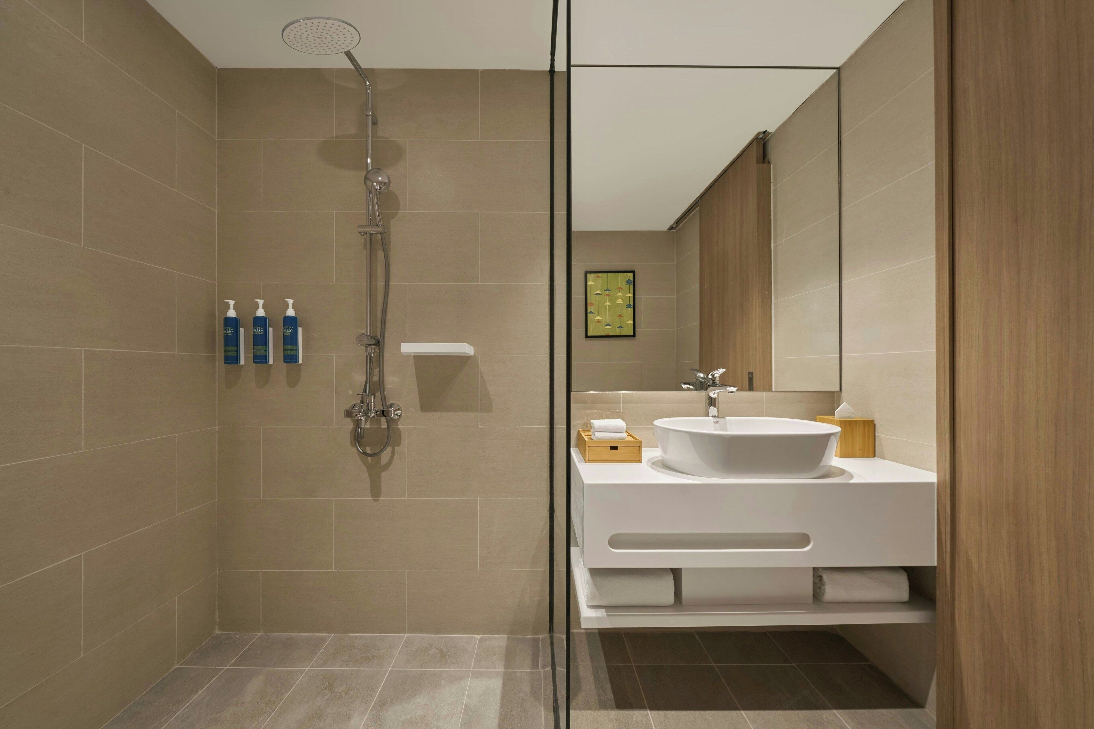 Un baño moderno con ducha, lavamanos y espejo.