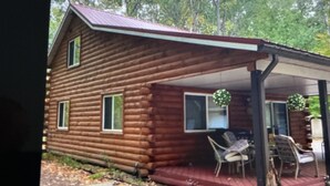 A log cabin with a covered porch and two chairs.