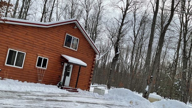 A wooden cabin with a snow-covered porch and a small porch area.