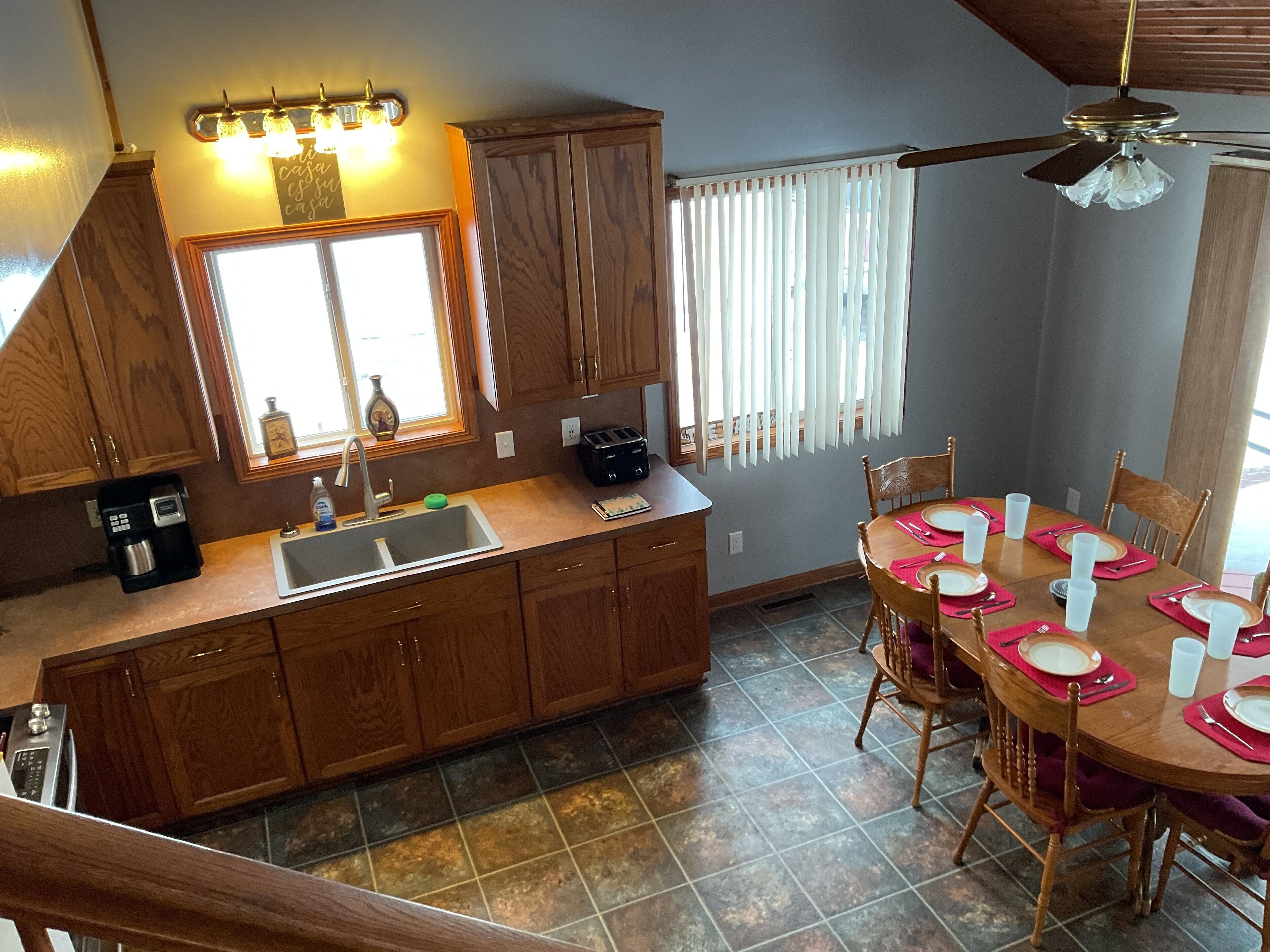 A kitchen with wooden cabinets, a sink, and a dining area with a table set for four.