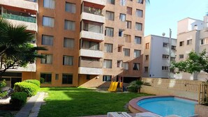 A residential building with a swimming pool, a small grassy area, and a slide. - Central apartment/studio family friends and couples (Santiago)