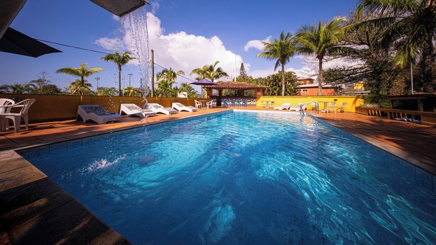 A swimming pool with lounge chairs and a water feature. - Hotel Cia do Mar (Bertioga)