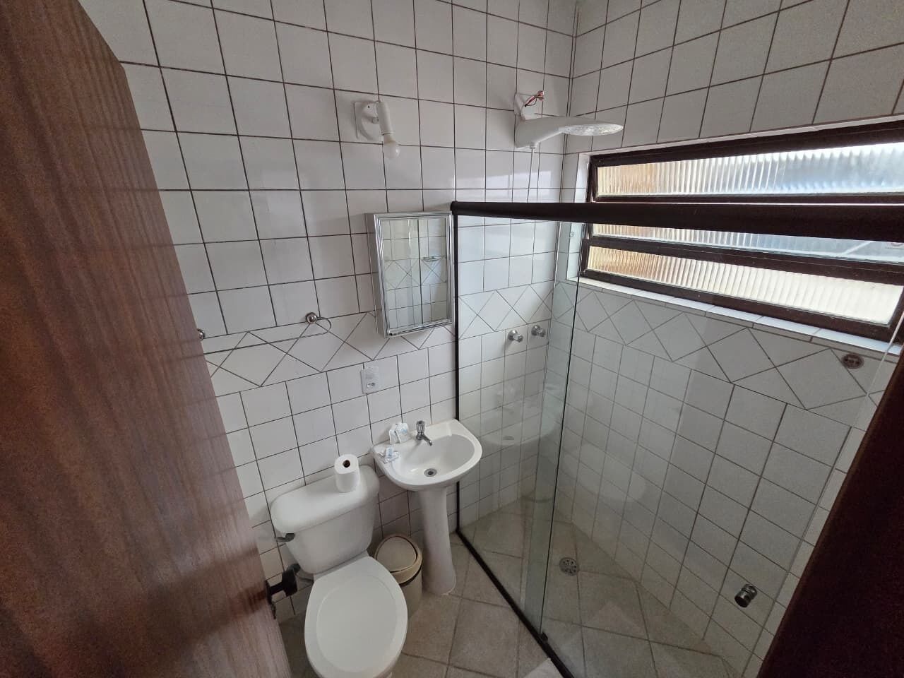 Une petite salle de bain comprenant des toilettes, un lavabo et une douche à parois en verre.