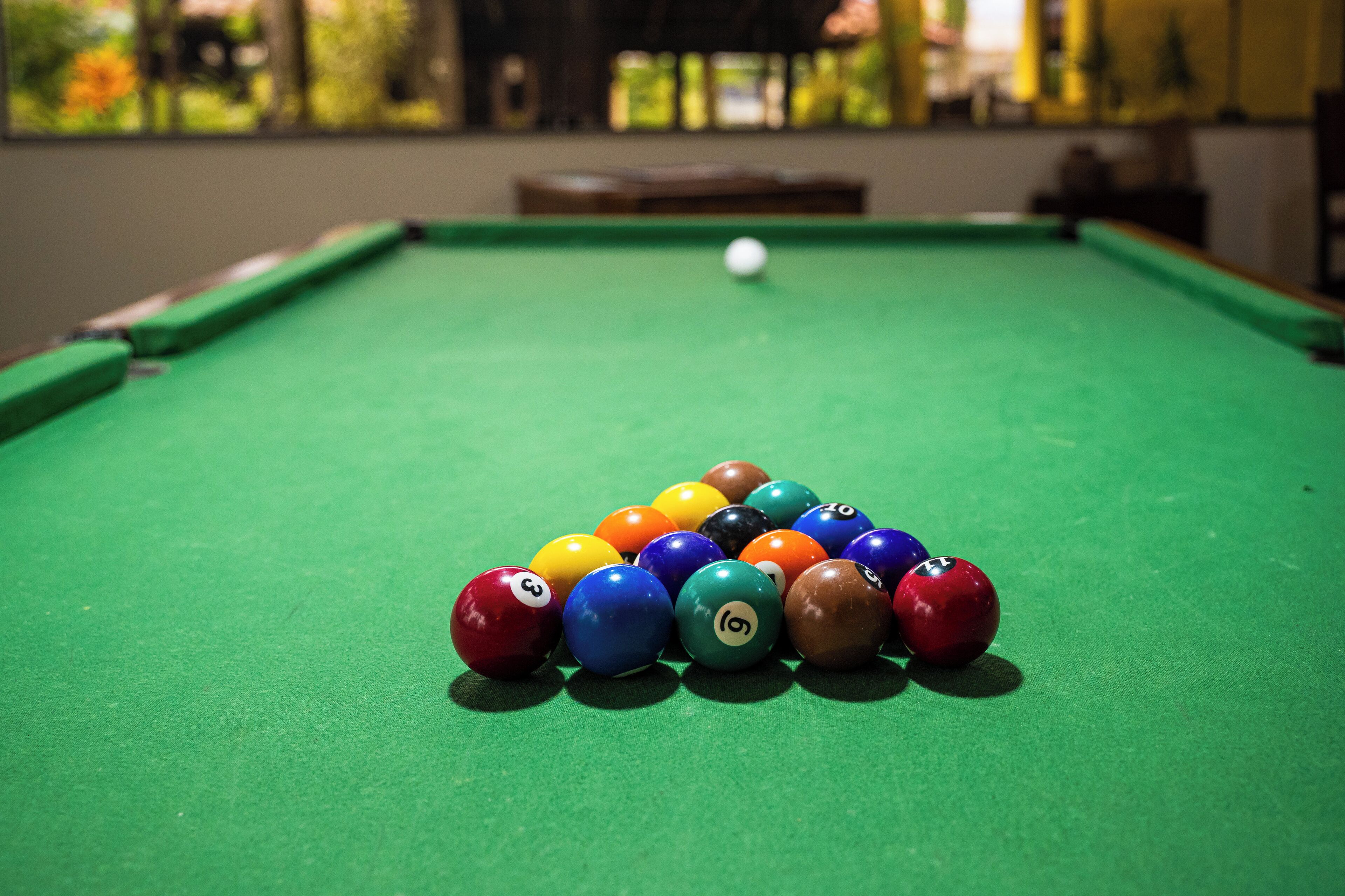 A pool table with a green felt surface and a white cue ball.