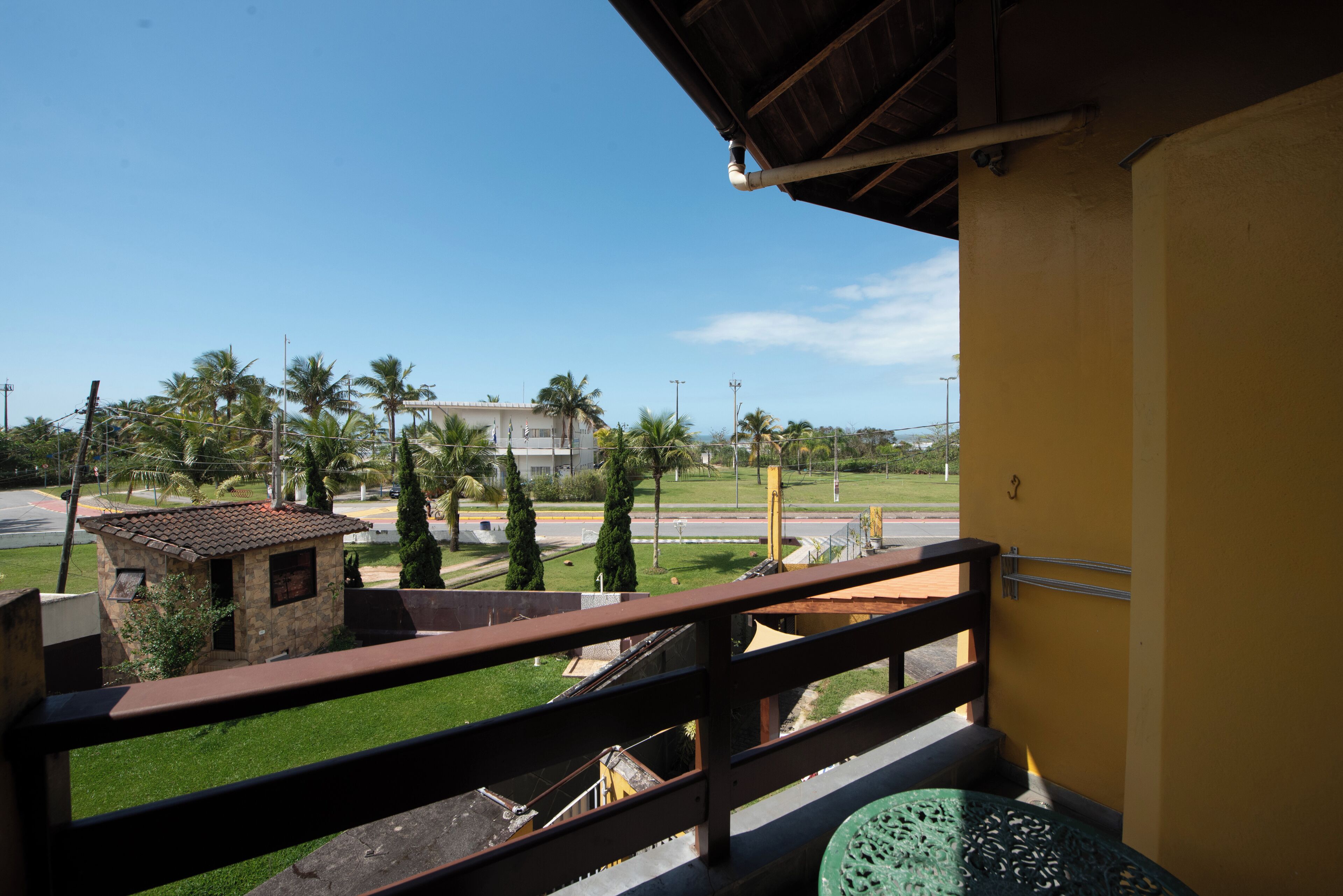 A balcony with a view of a building, palm trees, and a grassy area.