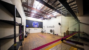 A gym with wooden floors, exercise equipment, and a logo on the wall. - Hotel Cia do Mar (Bertioga)
