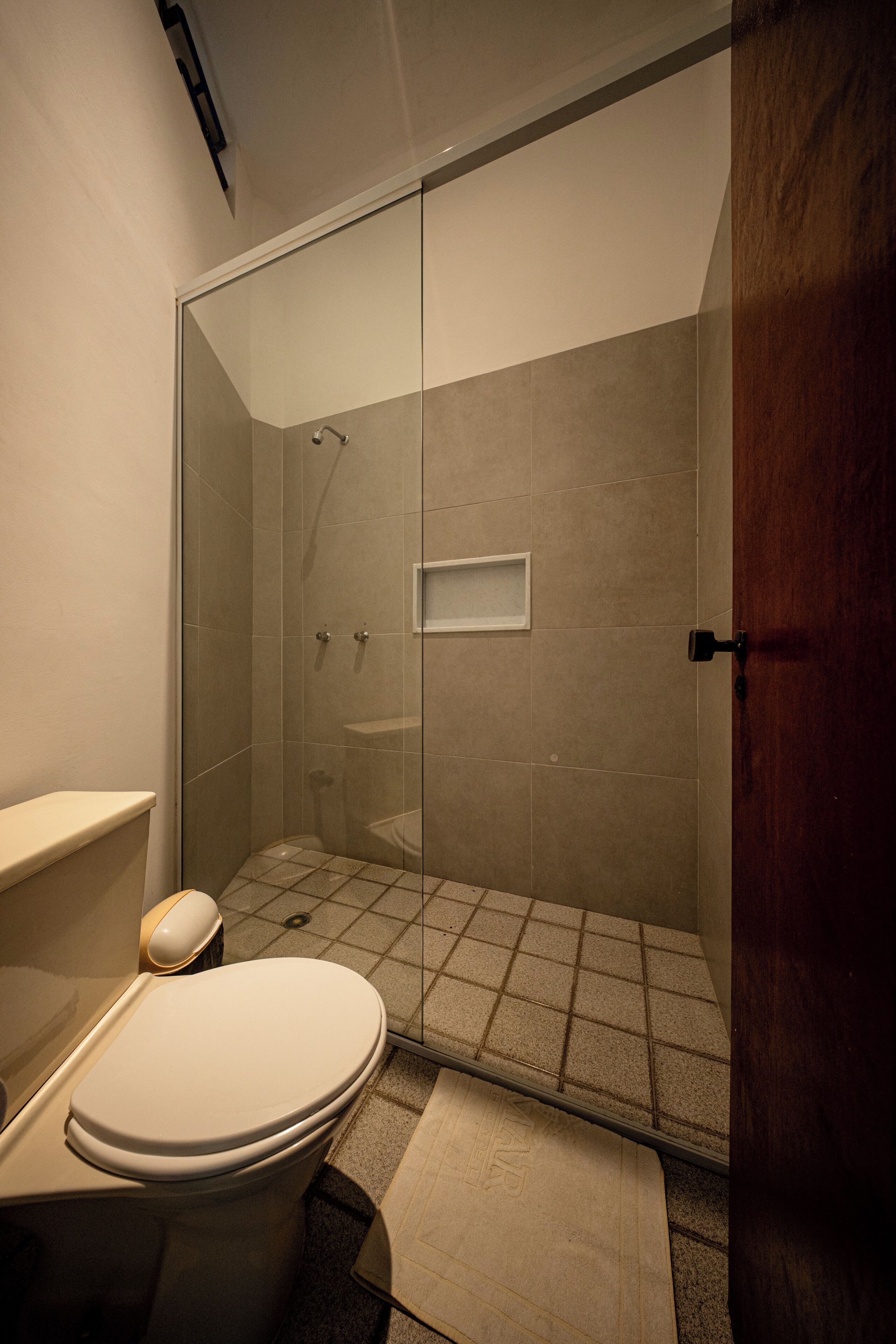A modern bathroom with a glass-enclosed shower, a toilet, and a sink.