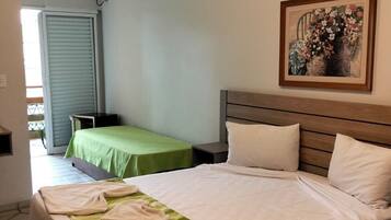 Quarto de hotel com uma cama, uma cama menor, um quadro e uma porta deslizante.