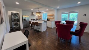 Una cocina moderna con una isla central, electrodomésticos integrados y un comedor con sillas rojas.