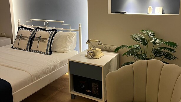 A modern bedroom with a large bed, bedside tables, a chair, and a wall-mounted TV.
