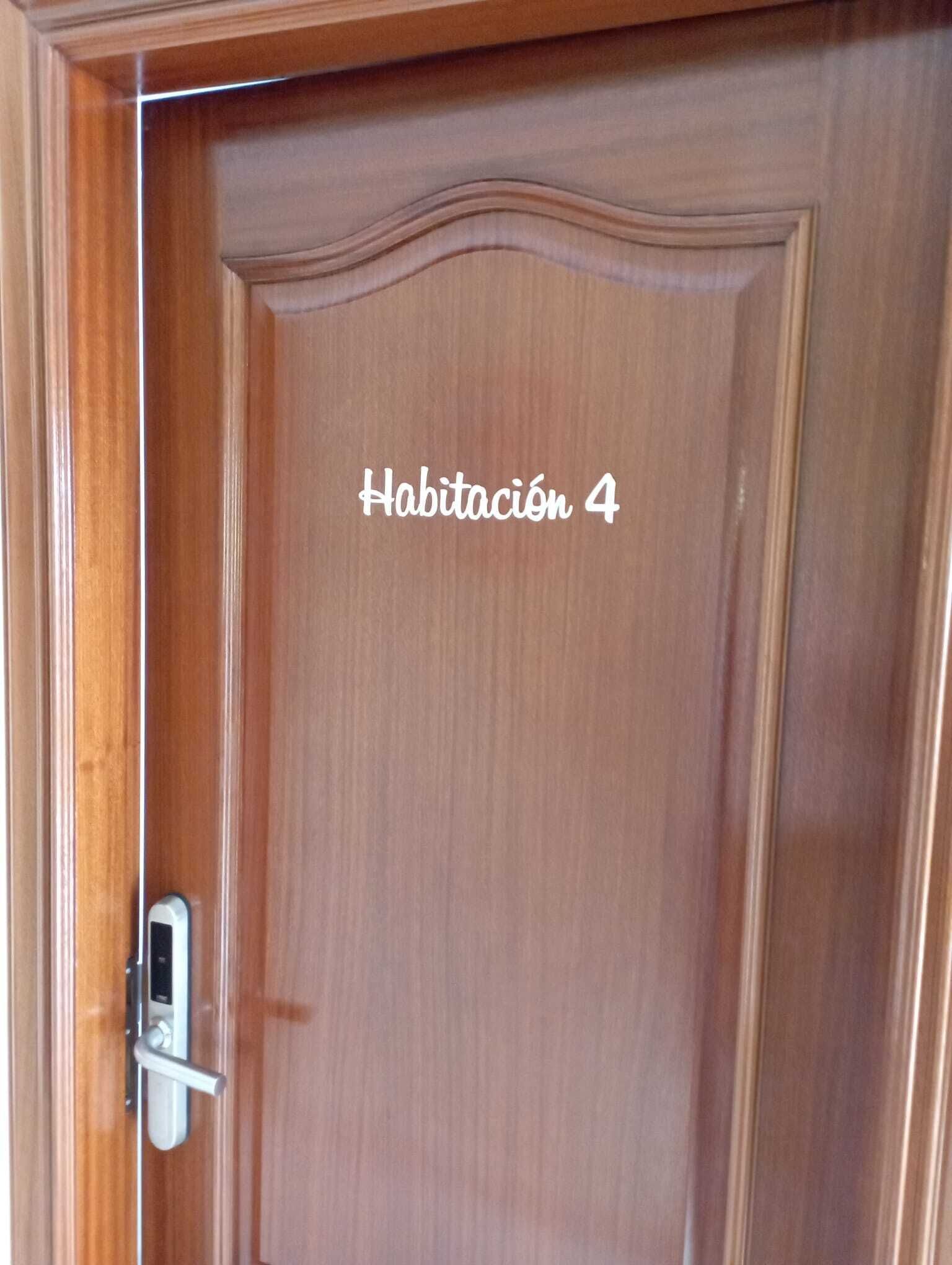 Une porte en bois dotée d’un verrou numérique et portant l’inscription « Habitación 4 », qui indique qu’il s’agit de la chambre numéro 4.