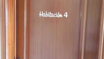 Une porte en bois dotée d’un verrou numérique et portant l’inscription « Habitación 4 », qui indique qu’il s’agit de la chambre numéro 4.