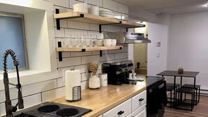 A modern kitchen with white cabinetry, a wooden countertop, and a built-in oven. There are shelves above the counter holding dishes and glasses. - Centrally Located Basement Apartment, Newly Remodeled, Pets Welcome (Missoula)