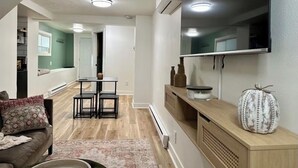 A modern living room with a sofa, coffee table, and a TV mounted on the wall. There is a wooden cabinet with decorative items and a small pumpkin on top. - Centrally Located Basement Apartment, Newly Remodeled, Pets Welcome (Missoula)