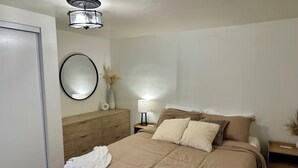 A bedroom with a bed, a dresser, a nightstand, a lamp, and a mirror. - Centrally Located Basement Apartment, Newly Remodeled, Pets Welcome (Missoula)