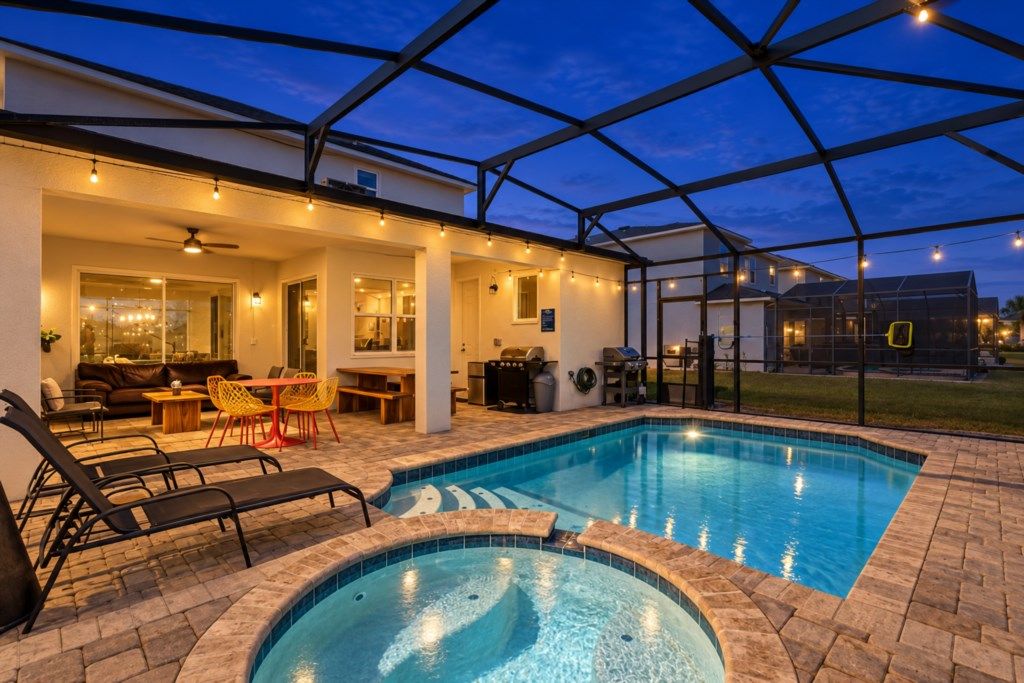 A swimming pool with a sunken hot tub, outdoor seating, and a covered patio area.