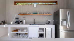 A modern kitchen with white cabinetry, a stainless steel refrigerator, and a coffee maker.