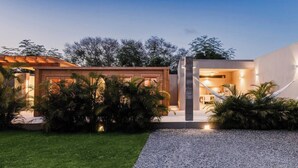 A modern house with a well-maintained garden, a gravel driveway, and a wooden structure.