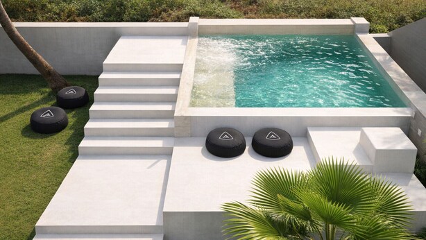 A modern outdoor pool area with steps leading to the water, surrounded by white concrete walls and black circular cushions.