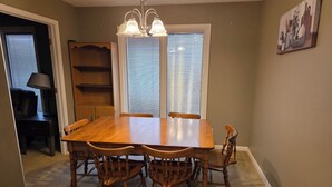 Un comedor con una mesa y sillas de madera, un candelabro y un cuadro en la pared.