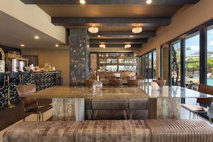 A modern dining area with a glass table, leather seating, and a view of the outdoors.