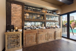 A kitchen with a brick wall, wooden cabinets, and a glass display shelf. - Barley House Hotel, Trademark Collection by Wyndham (Fort Lauderdale)