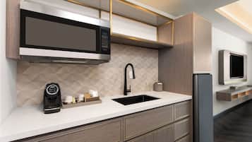 A modern kitchen with a built-in microwave, a coffee machine, a sink, and a refrigerator.