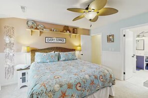 Bedroom with coastal bedding, wicker headboard, and an en-suite bathroom. - Cozy Coastal Escape | Pool, Bay Views, Beaches (Selbyville)