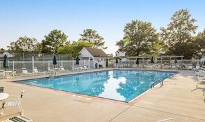 A large outdoor community pool is surrounded by patio seating and a white fence. - Cozy Coastal Escape | Pool, Bay Views, Beaches (Selbyville)