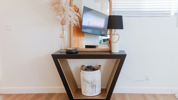 Une coiffeuse moderne avec un miroir, une télévision et une lampe.