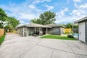 Une maison d’habitation dotée d’un patio couvert, d’une pelouse et d’une piscine.