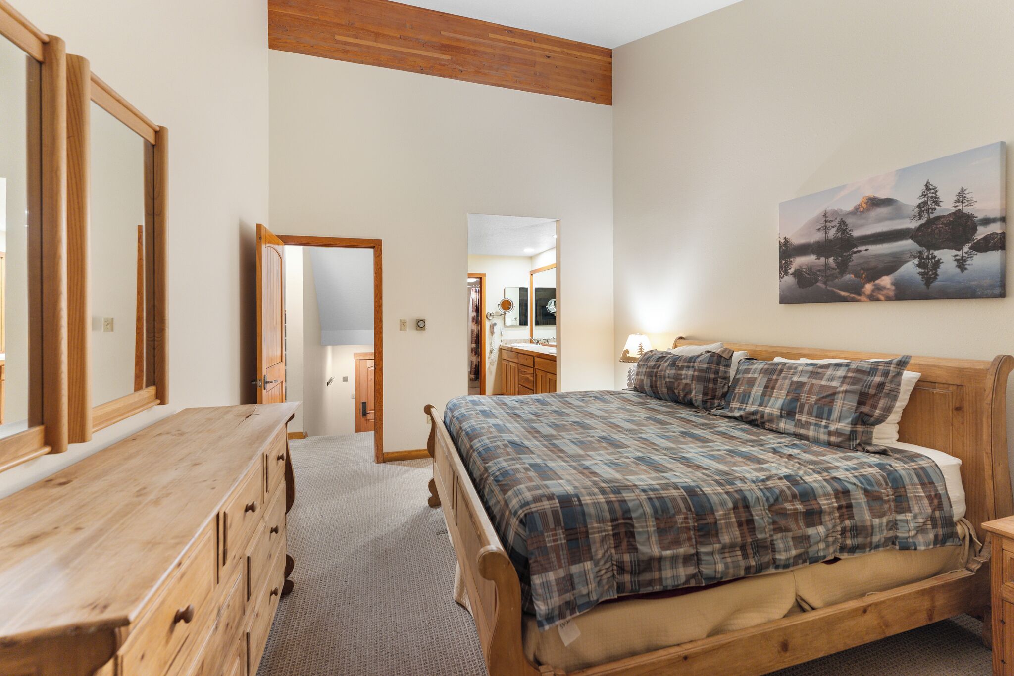 A bedroom with a wooden bed, a wooden dresser, and a large mirror.