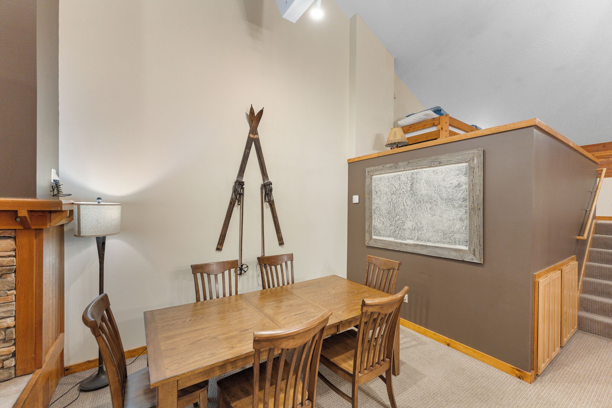 A dining area with a wooden table and chairs, a lamp, and a telescope on the wall.