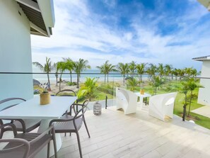 Un balcon avec vue sur la plage, une table avec des chaises et une plante en pot.