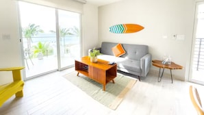 Een moderne woonkamer met een grijze bank, een houten salontafel en een bijzettafeltje.