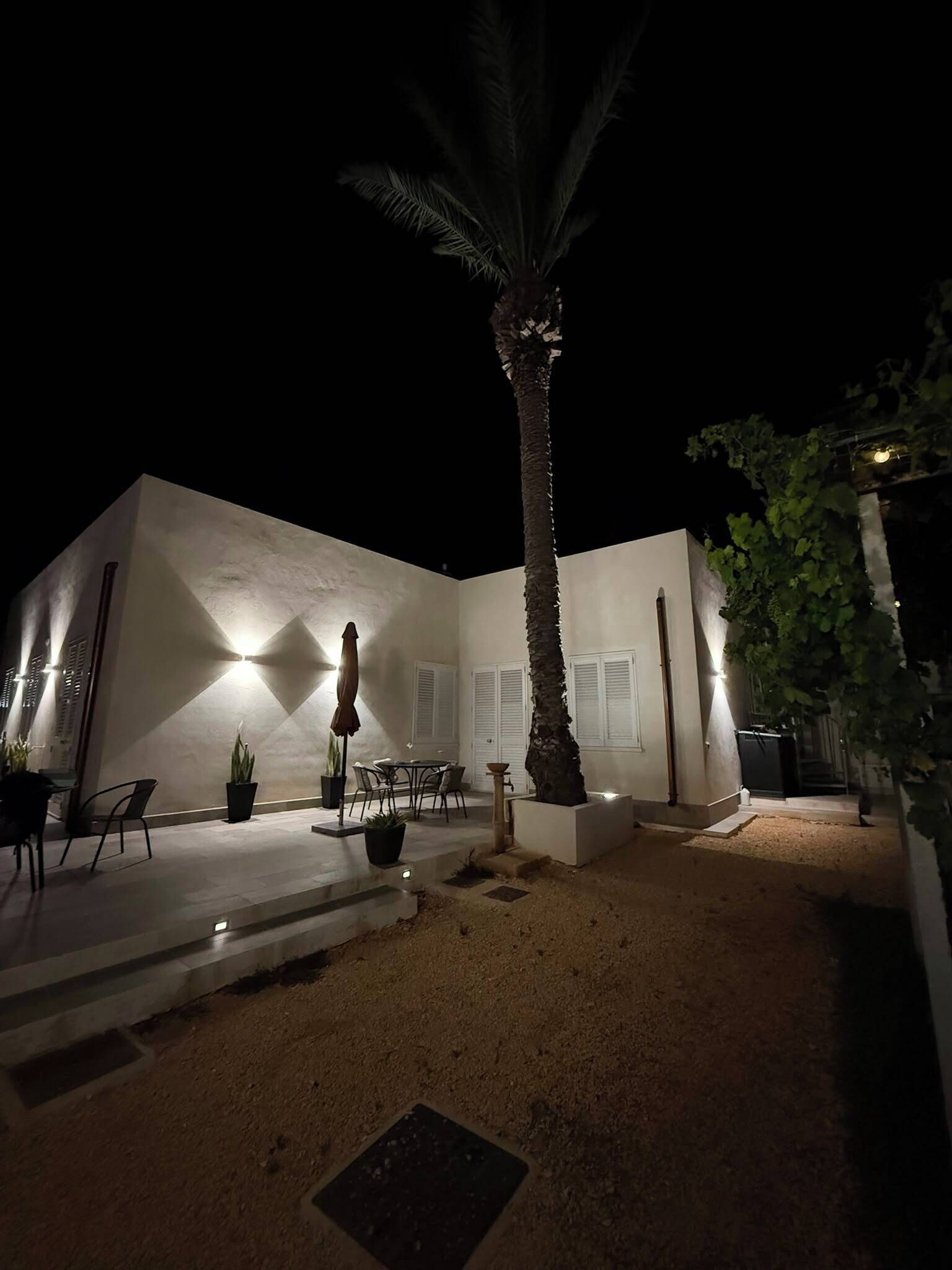Un edificio bianco con un patio, una palma e mobili da esterno.