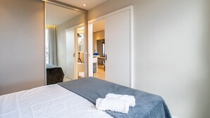A modern hotel room with a large bed, a mirror, and a view into the bathroom and kitchen area. - Condominium With Pool in Downtown Florianopolis - Cjos (Florianópolis)