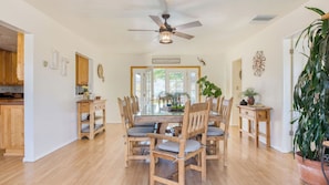 A dining area with a wooden table and chairs, a ceiling fan, and a kitchen visible through an open door. - Desert Shadows by Avantstay Breathtaking Views & Pool (Joshua Tree)