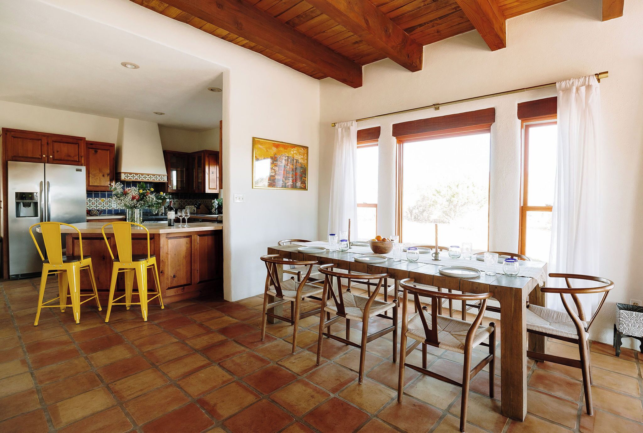A kitchen with a large island, wooden cabinets, and yellow chairs.