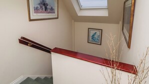 A staircase with a red handrail, a skylight, and two framed pictures on the walls. - Grange Cottage (Belford)